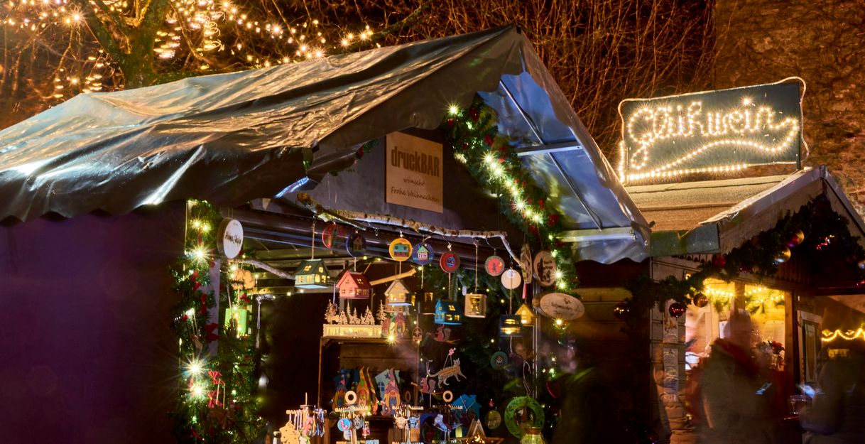 Ein festlich beleuchteter Stand, geschmückt mit Lichtern und Weihnachtsdekoration.